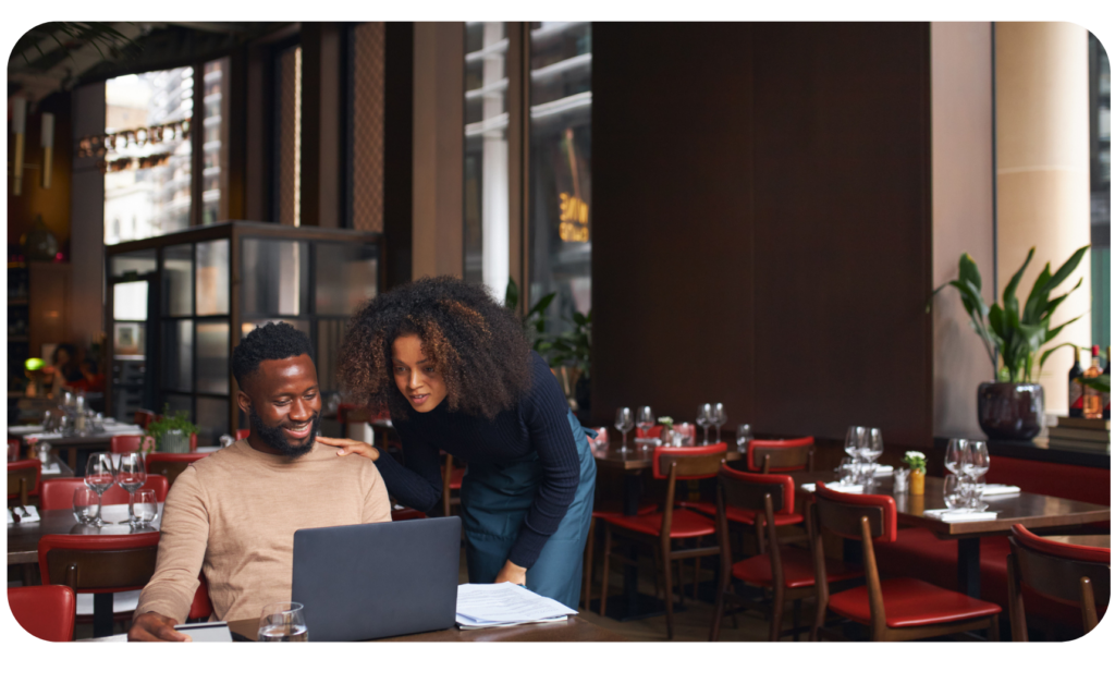 Man and woman sitting down at a laptop doing payroll